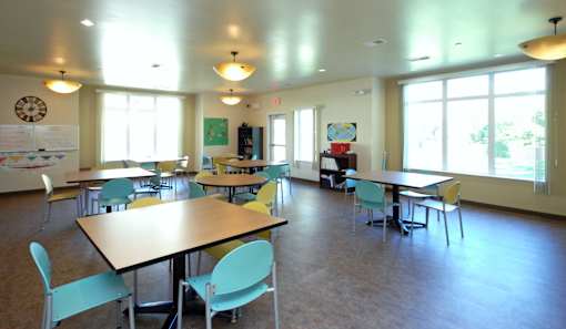 A room with tables and chairs and a whiteboard on the wall.