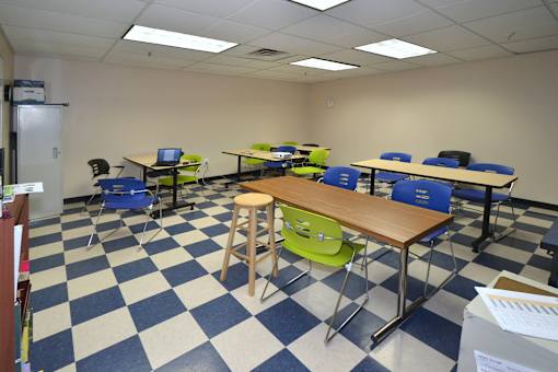 A classroom with blue and white checkered floor and tables with chairs.