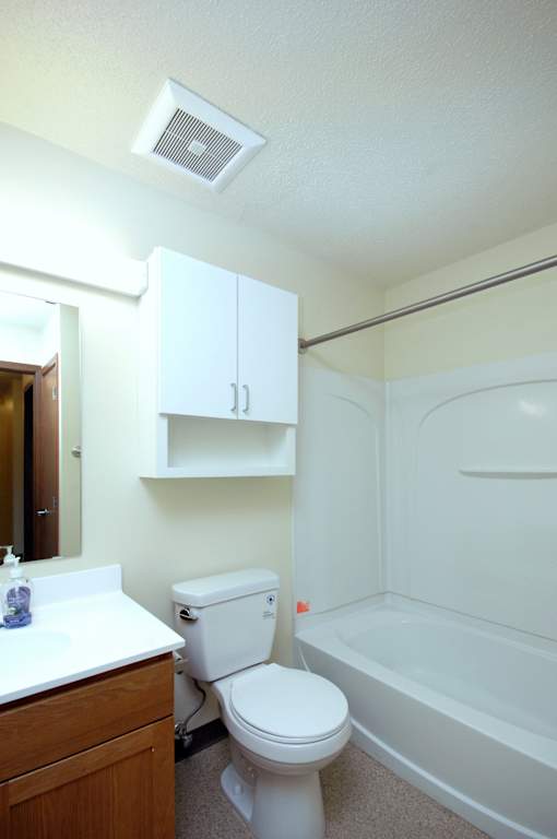A white toilet sits in a bathroom next to a bathtub.