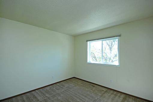 A room with a window and carpeted floor.