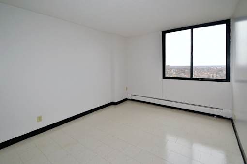 Empty room with a window overlooking a cityscape.