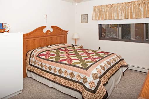A bed with a quilt on it in a bedroom.