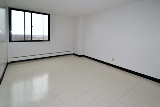 A large empty room with a window overlooking a cityscape.