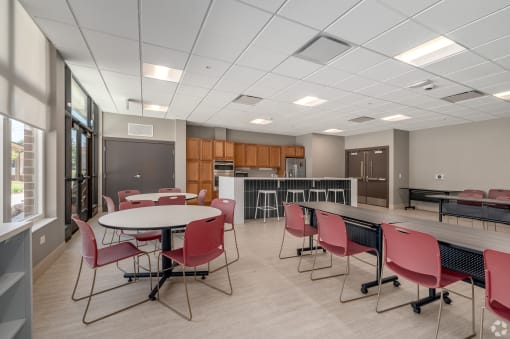 a large room with tables and chairs and a kitchen