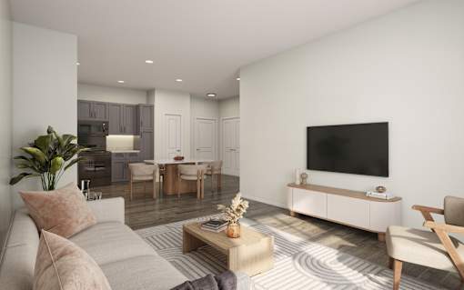 A modern living room with a grey sofa, a wooden coffee table, and a television on a white cabinet.