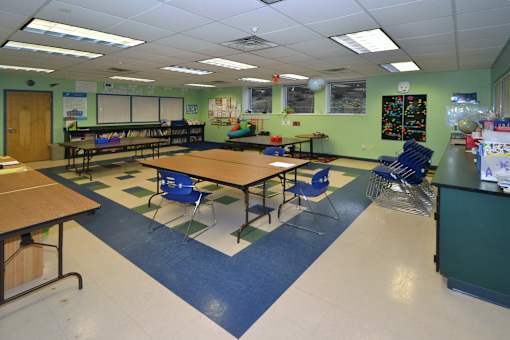 A classroom with tables and chairs and a whiteboard.