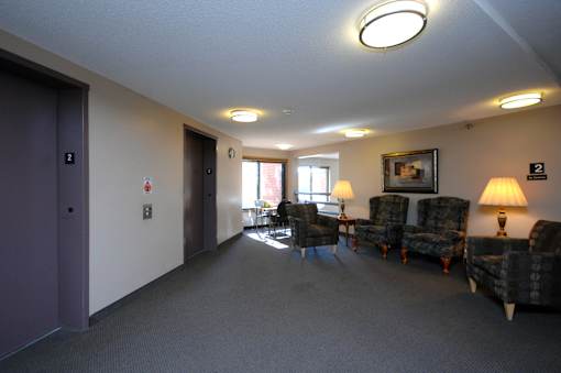A hallway with chairs and a lamp on the right side.