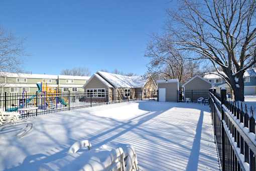 A snow-covered playground with a slide and a fence.