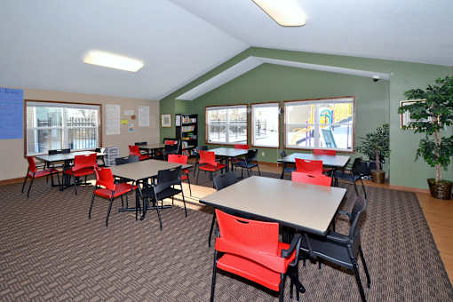 A room with tables and chairs and a carpet.