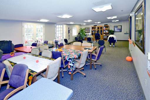 A white counter is in the middle of a room with tables and chairs.