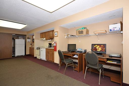 A room with a desk, chairs, and a refrigerator.