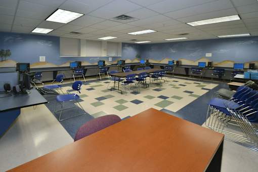 A classroom with blue chairs and desks.