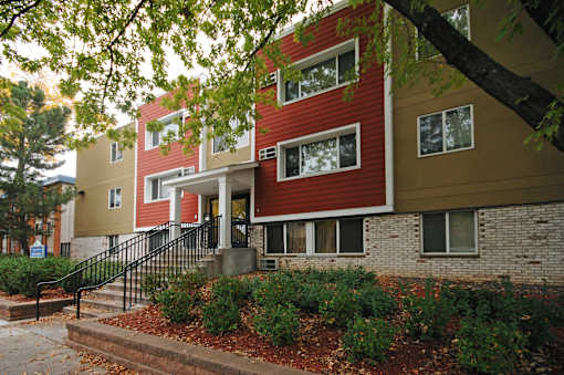 A red and beige building with a black railing on the steps.