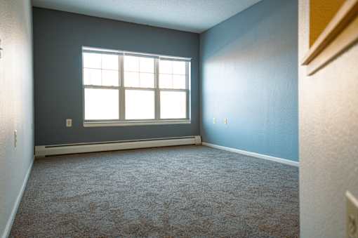 A room with a window and carpeted floor.