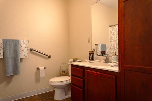 A bathroom with a toilet, sink, and mirror.