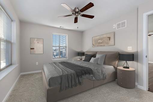 A bedroom with a bed, nightstands, and a ceiling fan.