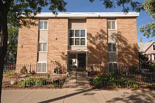 A brown brick building with a black gate in front.