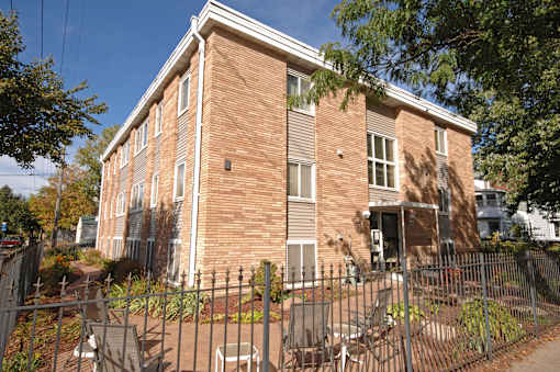 A red brick building with a black fence in front.