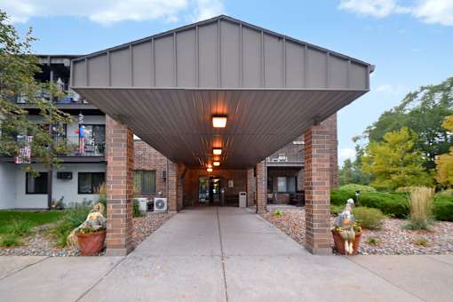 A covered walkway with lights underneath and potted plants on either side.