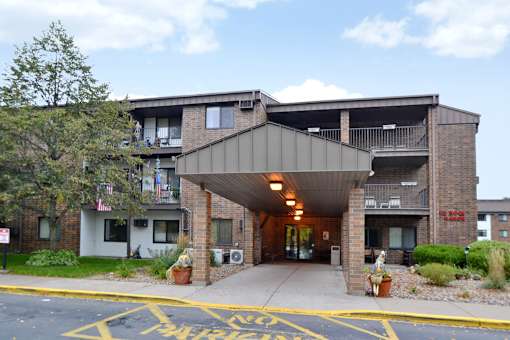 A building with a covered walkway entrance and a yellow painted parking area in front.