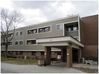 A building with a brown and beige exterior and a covered walkway.