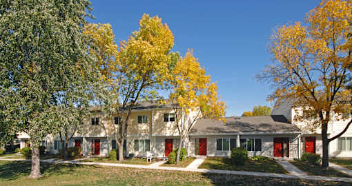 A row of houses with trees in front of them.