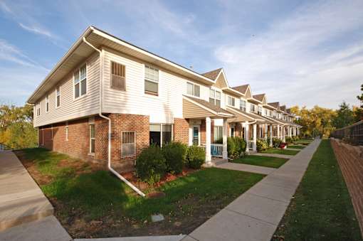 A long row of houses with a sidewalk in front.