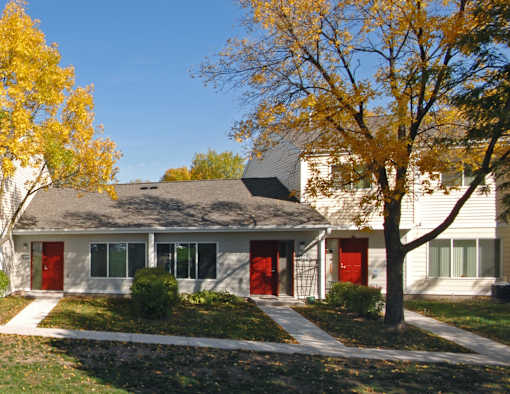 A house with red doors and a tree with yellow leaves.