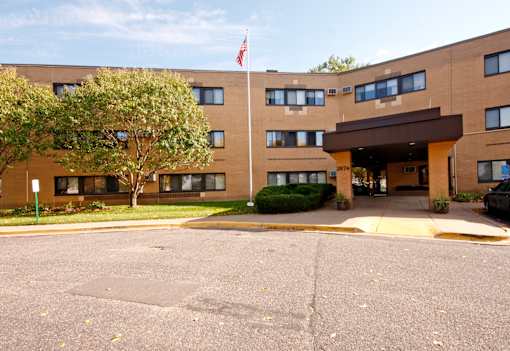 A building with a flag on top and a tree in front.
