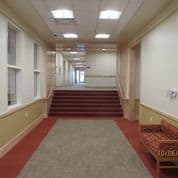 A long hallway with a staircase and a bench.