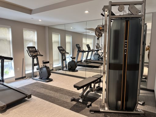 a gym with cardio equipment and mirrors in a building
