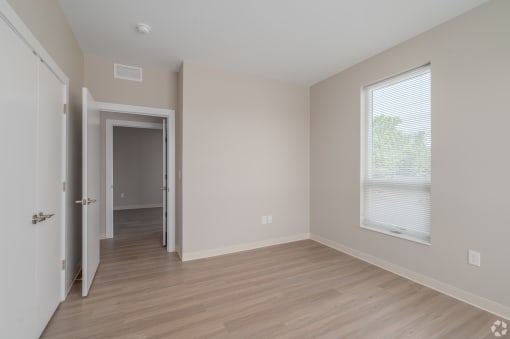 an empty bedroom with hardwood flooring and a large window
