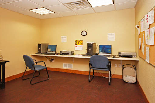 A room with two chairs and two computers on a desk.