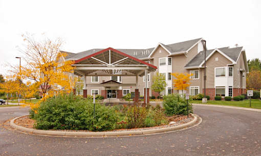 A large building with a red roof and a circular driveway in front.