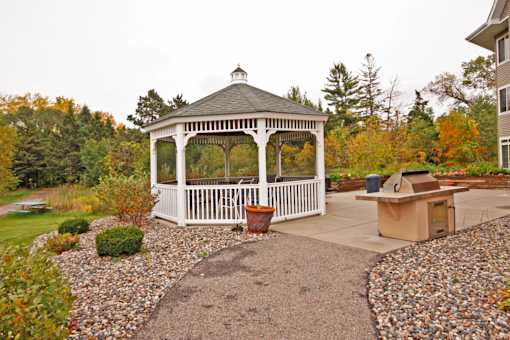 A gazebo is surrounded by a gravel area and a small garden.