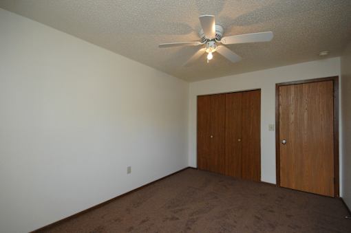 A room with a ceiling fan and two doors.