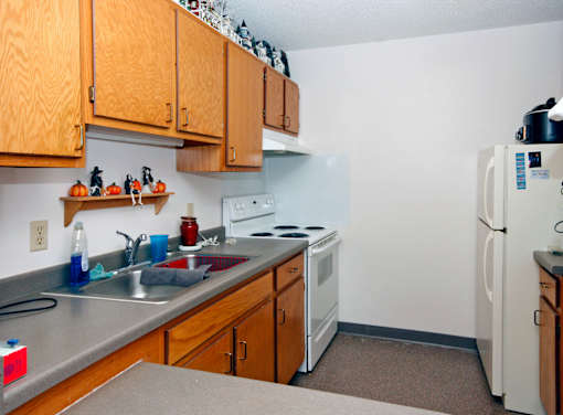 A kitchen with a white refrigerator, white stove, and wooden cabinets.