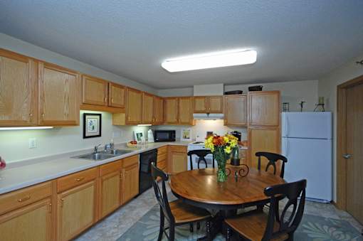 A kitchen with wooden cabinets and a table with chairs.