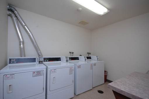 A room with two washing machines and a pipe.