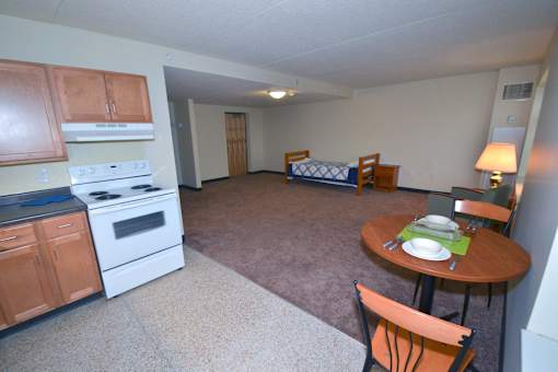 A kitchen with a stove top oven and a dining table with chairs.