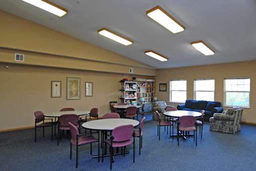 A room with tables and chairs and a bookcase.