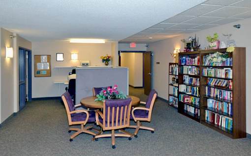 A room with a table, chairs, and a bookshelf.