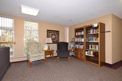 A room with a bookshelf, a chair, and a table.