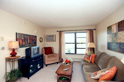 A living room with a brown couch, a black dresser, a red lamp, and a painting on the wall.