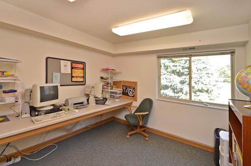 A computer desk with a monitor, keyboard, and mouse.