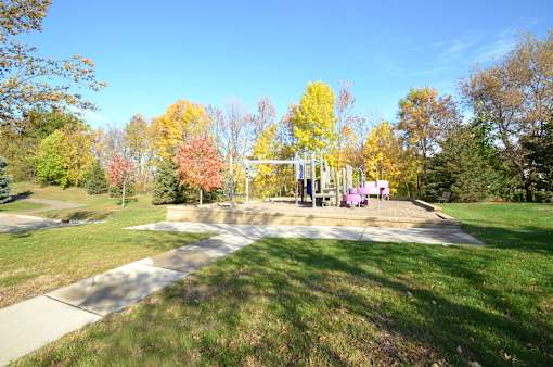 A park with a playground and trees in autumn colors.