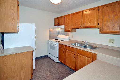A kitchen with a white refrigerator, white stove, and brown cabinets.