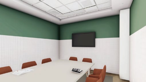 a meeting room with a table and chairs and a tv on the wall