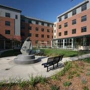 A statue is in the middle of a courtyard with a bench to the right.