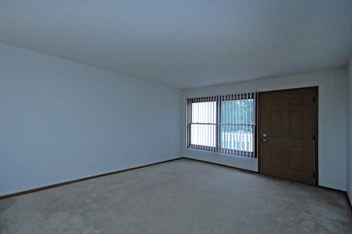 A room with a brown door and a window with blinds.